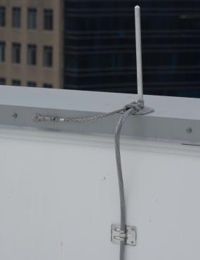 The parapet mounted air terminal has a secondary bond to the metal coping cap to provide continuity.