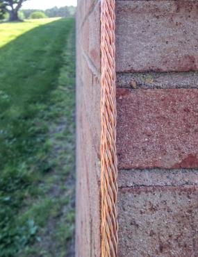 A copper conductor cable visually blends into the reddish brick wall. Aligning it with the building's architectural edges further reduces its visual impact.