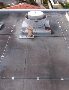 Conductor cables on the rooftop and parapet connect to air terminals and rooftop mechanical and communication equipment.